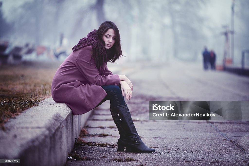 Smutny Młoda kobieta siedzi na zewnątrz - Zbiór zdjęć royalty-free (20-29 lat)