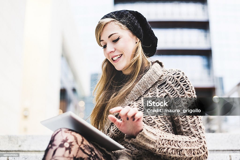 Woman using a digital tablet outdoor Blonde woman sitting outdoor and using a digital tablet. Citylife. Autumn Stock Photo
