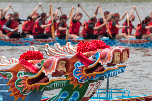 Taipei, Taiwan, June 20, 2015 - A dragon boat team passes in the background behind the dragon heads of three dragon boats during the annual dragon boat race on Keelung (Jilong) River in Taipei.