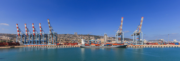 Haifa, Israel - July 10, 2015: View of the city of Haifa Israel, from Haifa's Port  with container ship and Carmel mountain in the background.