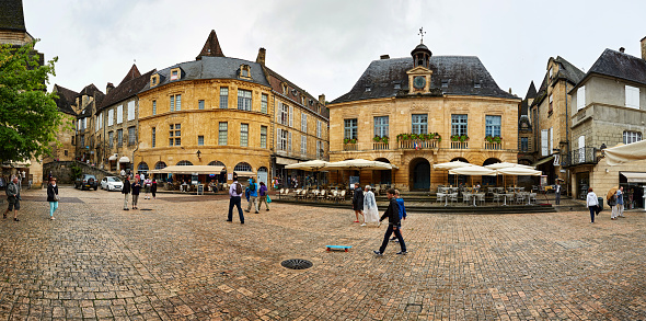 Sarlat, France - June 14, 2015: Town square in Sarlat France. Tourists are pictured walking on the cobblestone street lined with restaurants and old stone buildings