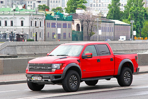 Moscow, Russia - July 7, 2012: Red pickup truck Ford F-150 Raptor drives at the city street.