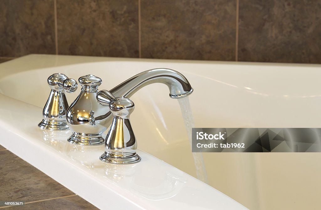 New Chrome Faucet in Master Bath Tub Closeup horizontal photo of chrome faucet running water into soaking tub in master bathroom Architecture Stock Photo