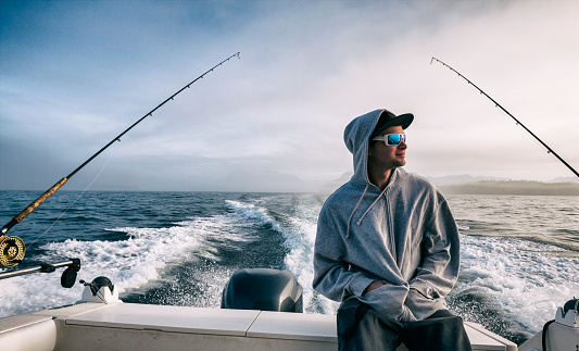 Young man deep sea fishing in the pacific ocean off the west coast of British Columbia, Canada.