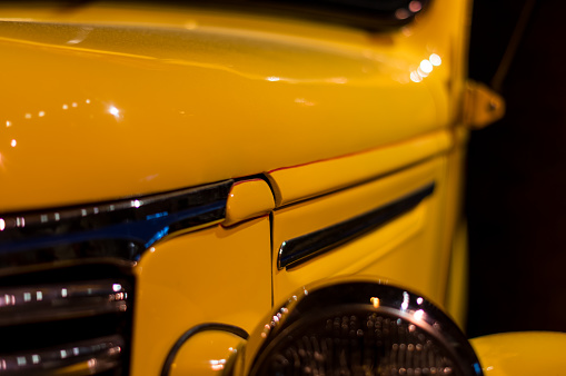 An old classic Chevy car is shown from a close-up perspective. The image is taken from the front looking back from the automobile's left side. The shiny new yellow paint job makes the car look great.