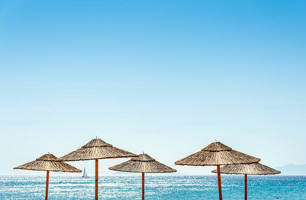 Five sun umbrellas, the sea, horizon and one sailboat.