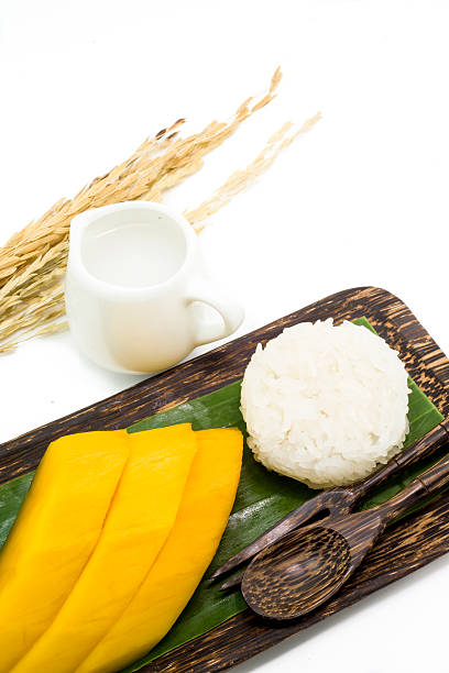 Thai dessert of mango with sticky rice served on palm wooden dish