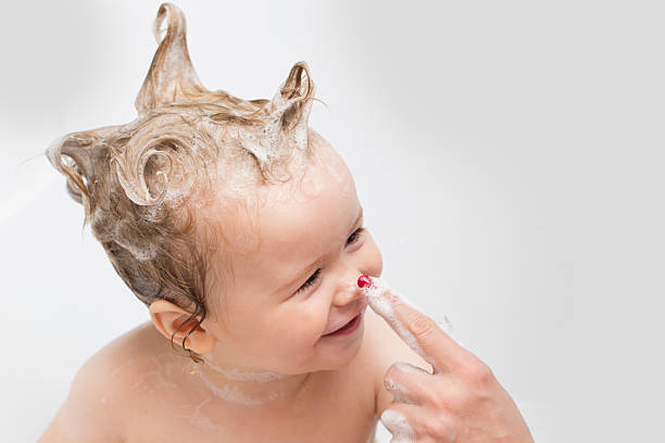 Baby boy in bath and mother's hand Little pretty wet baby boy in bath room with foam soap hair sitting and playing with mother's hand on white background, horizontal picture washing hair stock pictures, royalty-free photos & images