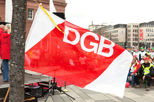 Wiesbaden, Germany - March 19, 2014: Participants of a warning strike and demonstration for higher wages in public services in the city center of Wiesbaden, Germany. In the foreground a flag of DGB. The demonstration was organized by german trade union verdi.