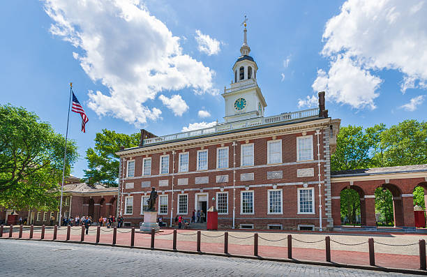 Independence Hall in Philadelphia, Pennsylvania, USA Philadelphia, PA, USA - May 18, 2014. Tourists are walking into Independence Hall is where both the United States Declaration of Independence and the United States Constitution were debated and adopted. American flag is seen on the right side of the photograph. The photograph was taken midday with full frame camera and Zeiss wide-angle lens. independence hall stock pictures, royalty-free photos & images