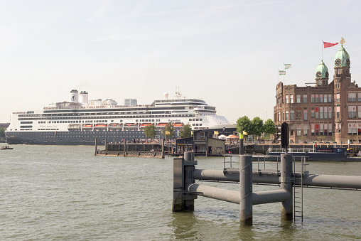 Rotterdam, The Netherlands - July 11, 2015: departure cruise ship Rotterdam of the Holland America Line from the Port of Rotterdam. On board and on quay people watch; old office of Holland America Line is now hotel New York.