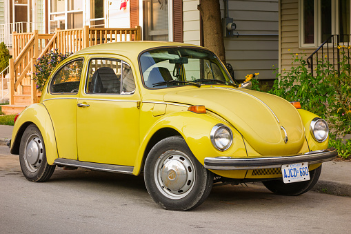 Hamilton, Canada - August 19, 2013: Yellow colored Volkswagen Beetle parked on a street.
