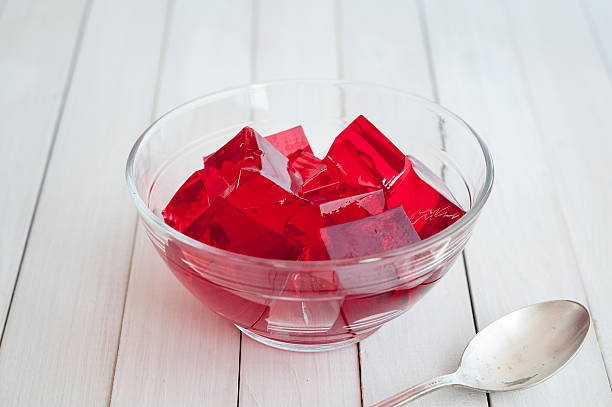 Red jelly cubes in glass bowl with silver spoon stock photo