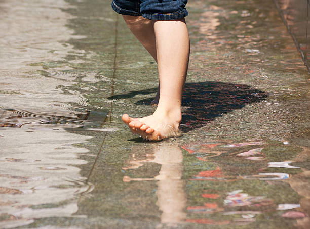 istock boy's feet playing the fountain 481078936