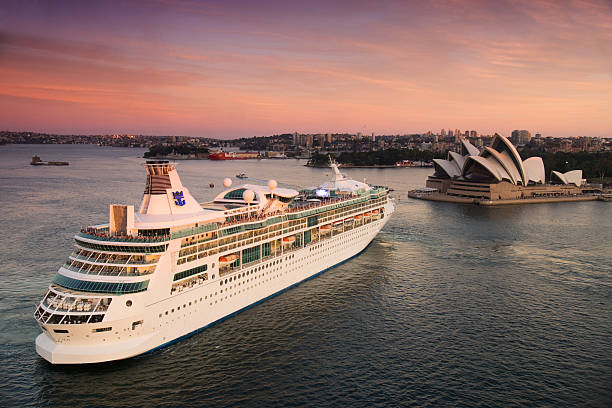 Rhapsody of the Seas leaves Sydney Sydney, Australia - March 18, 2014: The Rhapsody of the Seas cruise ship, operated by Royal Caribbean International, reverses past the Sydney Opera House as it prepares to depart on a trip at sunset. cirrus photos stock pictures, royalty-free photos & images