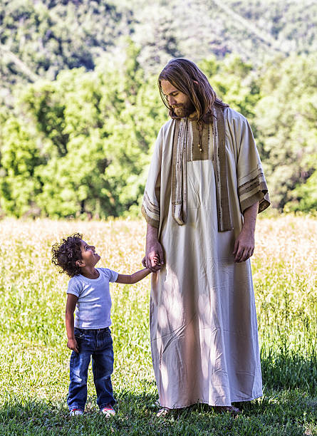 kleine junge holding hände mit jesus christ - serene people tranquil scene child god stock-fotos und bilder