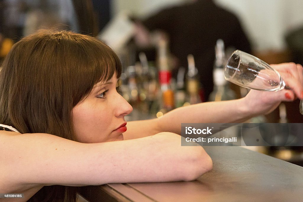 Depressed Woman with empty glass Young woman looking at her empty glass at the bar counter. Loneliness Stock Photo