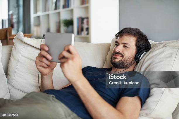 Deitada No Sofá Com O Tablet Na Mão - Fotografias de stock e mais imagens de Tablet digital - Tablet digital, Homens, Olhar atentamente