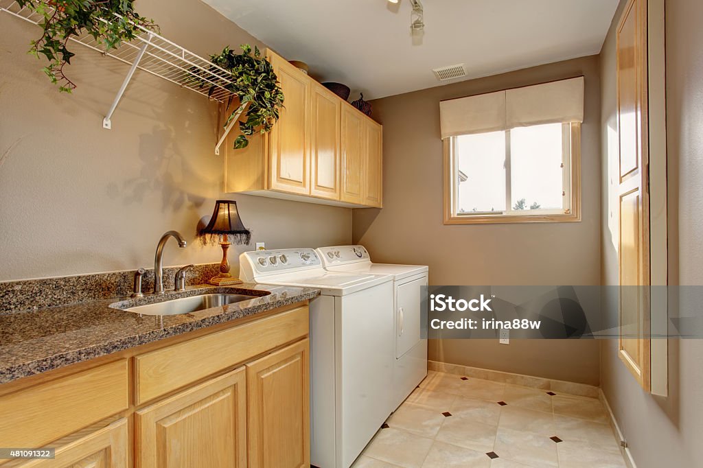 Traditional laundry room with nice counters and washer dryer com Traditional laundry room with tile floor, and washer dryer combo. Utility Room Stock Photo