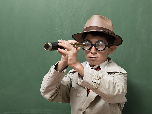 istock Little detective looking through hand held telescope on green blackboard 481091848