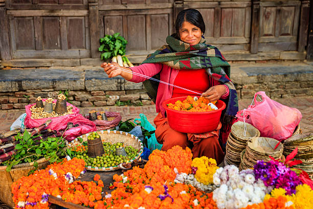Nepali street seller selling flowers and vegetables in Patan, Nepal Nepali young woman selling flowers vegetables on Durbar Square in Patan, Nepal.http://bhphoto.pl/IS/nepal_380.jpg bazaar market photos stock pictures, royalty-free photos & images