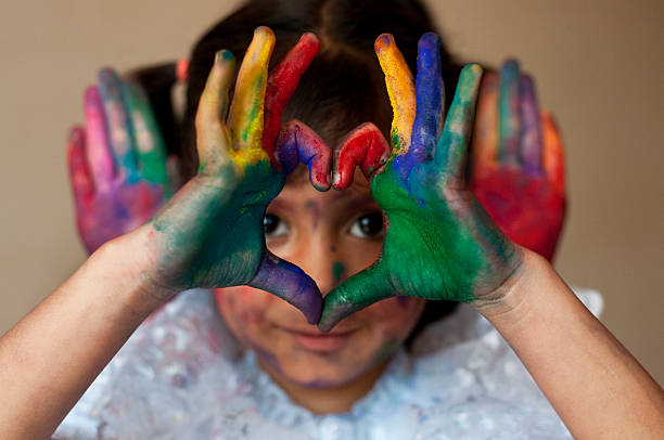 istock Small girl making heart shape with colorful hands 481098639