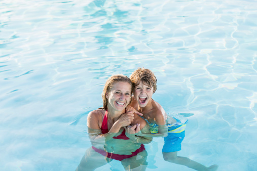 Mother (30s) and son (9 years) having fun in swimming pool.
