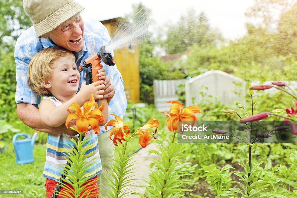 Grandmother and grandson in the garden Happy family watering flowers Gardening Stock Photo