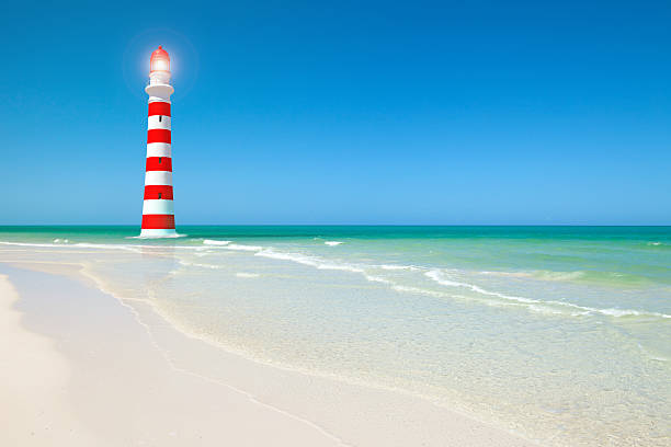 White and red lighthouse on a scenic tropical beach with white sands, turquoise water and blue sky on a sunny day. Light emits shining flare. Copy space on right side. 