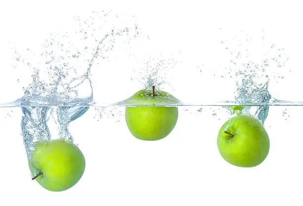 Fresh apples falling into water with splashes