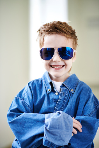 Cool little boy in too big denim shirt and sunglasses