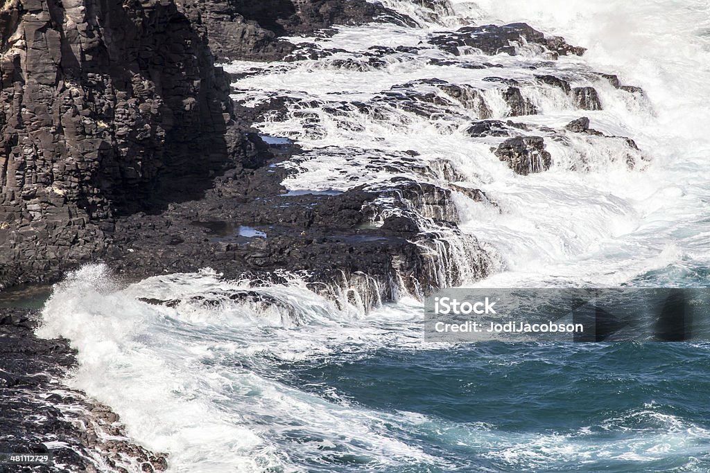 Waves crashing into lava rock formation in Kauai, Hawaii A view from a helicopter shows waves crashing into rock formations in Kauai, Hawaii.  RM Aerial View Stock Photo