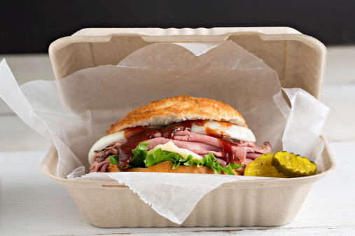 A high angle extreme close up of a barbecued beef sandwich packaged to go.