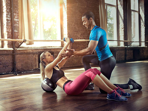 istock Fitness trainer helps women with exercise ball 481116294