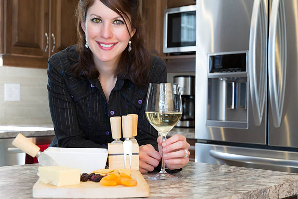 kobieta uśmiechając się trzymając kieliszek wina i serów - appliance floor fruit designer zdjęcia i obrazy z banku zdjęć