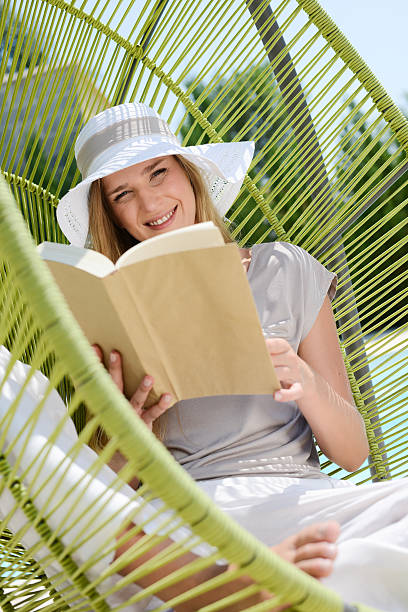 istock cheerful young blond woman reading relaxed swing by the pool 481129584