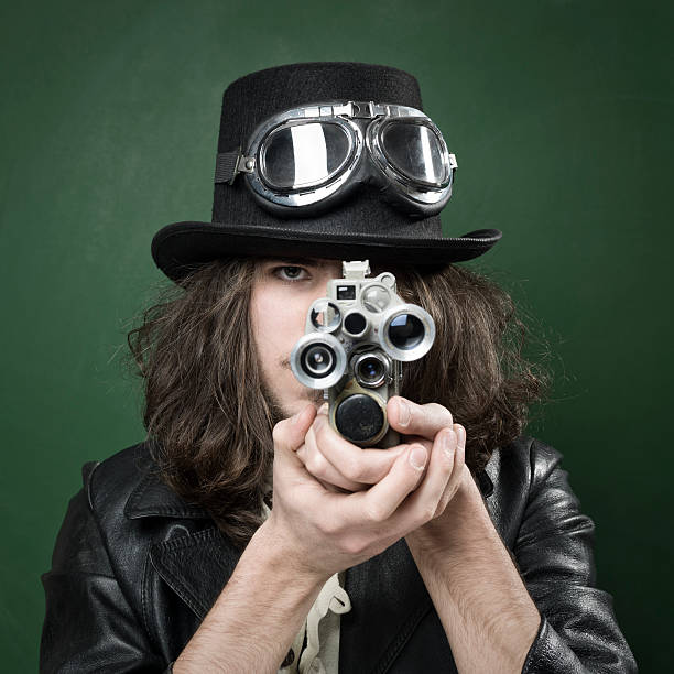 istock Young man in old fashioned style filming via antique camera 481131095