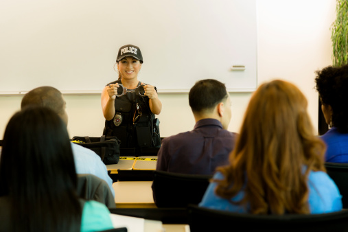 Latin policewoman speaks to police cadets in lecture hall;  or policewoman gives safety presentation to local community.