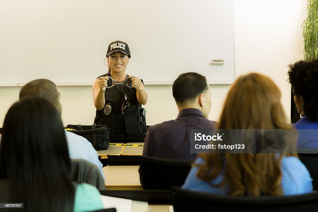 Law:  Policewoman speaks to police cadets or community. Latin policewoman speaks to police cadets in lecture hall;  or policewoman gives safety presentation to local community. Police Force Stock Photo