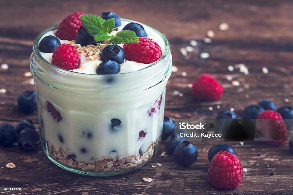 Yoghurt with Fresh Berries on Woden Table Serving of Yoghurt with Whole Fresh Blueberries, Raspberries and Oatmeal on Old Rustic Wooden Table Food Stock Photo