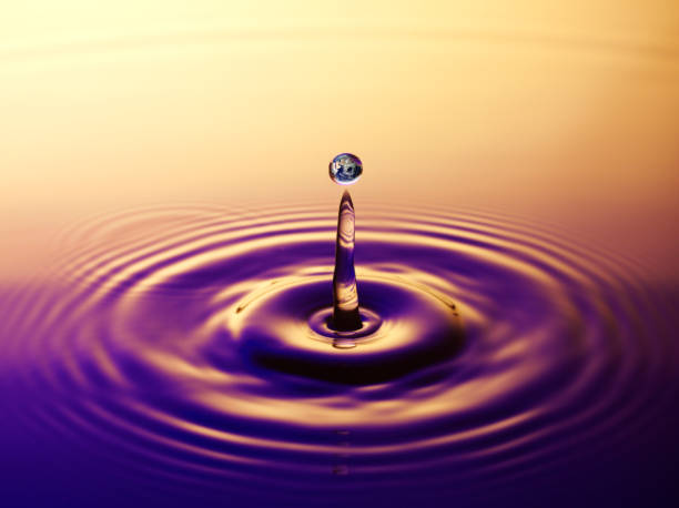 Reflection of the Earth in a Raindrop Splash Raindrop with a reflection of the earth on a blue/purple and gold background. water thinking bubble drop stock pictures, royalty-free photos & images