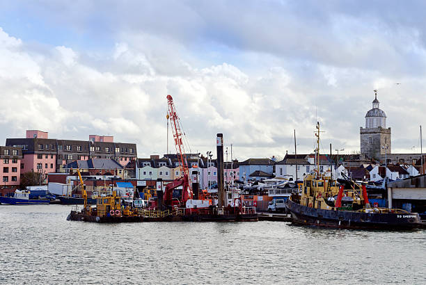 Portsmouth, Hampshire, England - November 1, 2012: A variety of boats in the Camber Docks, in Old Portsmouth, Hampshire. The Camber leads off Portsmouth Harbour and is the old original harbour. The old town is nearby and Portsmouth Cathedral can be seen to the right. (Background people. Overcast weather.)