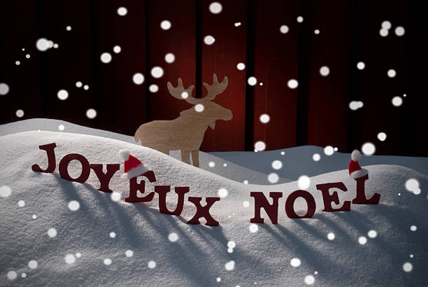 Red Letters Building French Word Joyeux Noel Means Merry Christmas As Decoration Card. Snow And Snowy Scenery With Snowflakes Moose And Santa Hat. Wooden Background. Christmas Atmosphere
