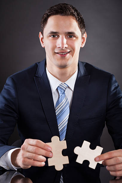 istock Smiling Businessman Joining Puzzle Pieces At Desk 481160842