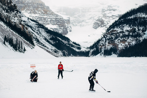 Lake Louise, Canada - February 15, 2015: Group of friends play Ice Hockey over the frozen Lake Louise in Banff National Park.