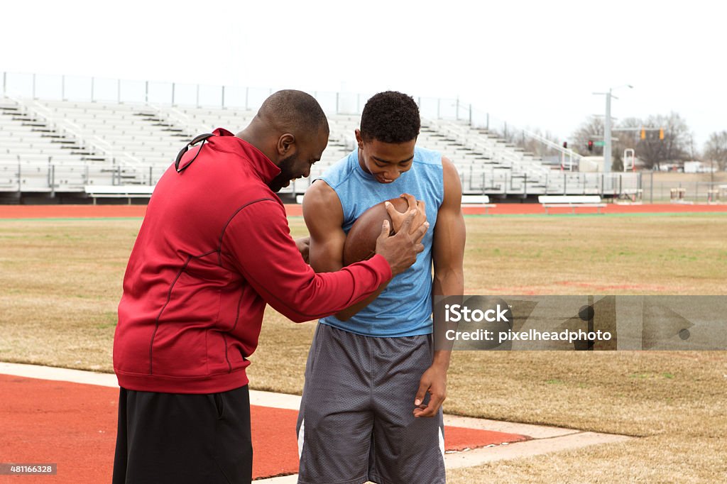 Football Training African American coach training an athlete for American football. American Football - Ball Stock Photo