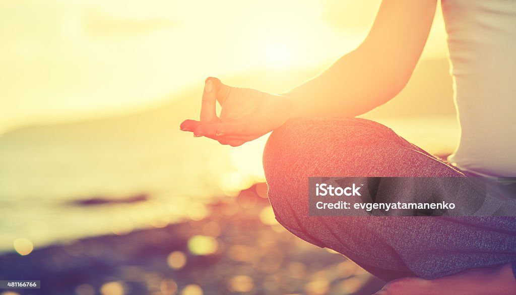 Yoga concept. hand woman practicing lotus pose on beach Yoga concept. hand woman practicing lotus pose on the beach at sunset Yoga Stock Photo