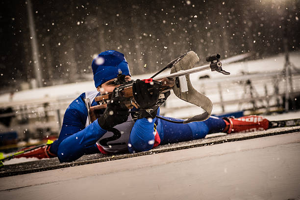 sportlichen mann zielen mit biathlon gewehr - biathlon stock-fotos und bilder