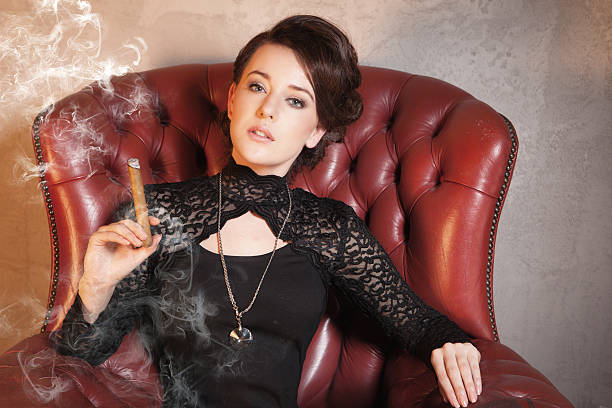 Beautiful brunette with cigare Beautiful lady is smoking cigare on stylish armchair - retro style smoking women luxury cigar stock pictures, royalty-free photos & images