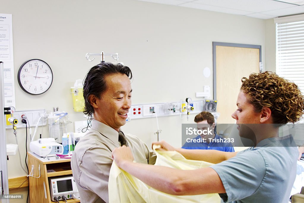 Médico colocando os braços em vestido pronto para entrega - Foto de stock de Adulto royalty-free